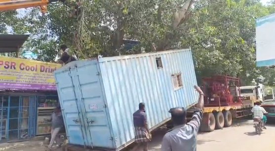 சேதமடைந்த சாலையில் சிக்கிய கண்டெய்னர் லாரி – மரக்கிளையில் மோதி கீழே சரிந்த கன்டெய்னர்
